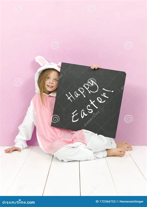 Pretty Blonde Girl With Cozy Rabbit Costume And Blackboard With Happy