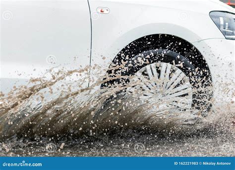 Car Motion Through Big Puddle Of Water Splashes From The Wheels On The