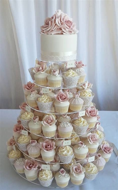 A Three Tiered Wedding Cake With Cupcakes On The Bottom And Pink Roses