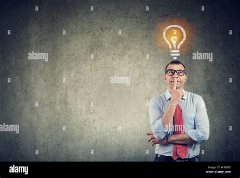 Portrait Of A Thinking Business Man Looking Up At Bright Light Bulb
