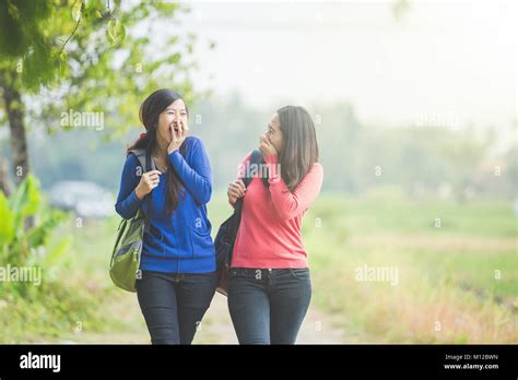 A Portrait Of Two Young Asian Students Chatting While Walking Together