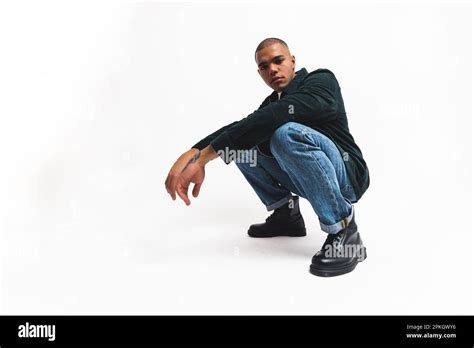 Serious Male Fashion Model Posing In Squat Pose And Looking To The