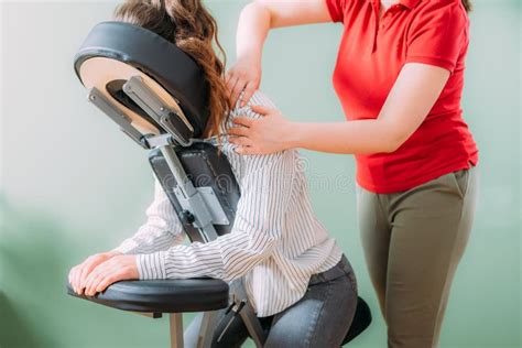 Female Employee Sitting On A Portable Massage Chair In Business Office Therapist Massaging Her