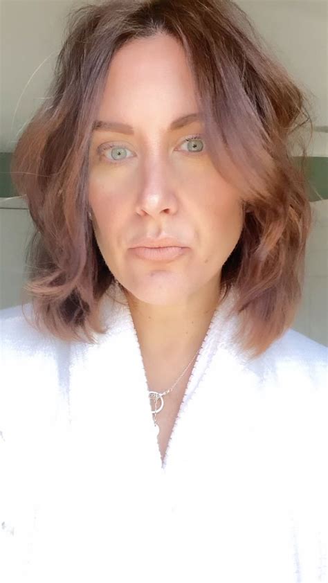A Woman With Brown Hair And Green Eyes Wearing A White Bathrobe Looking