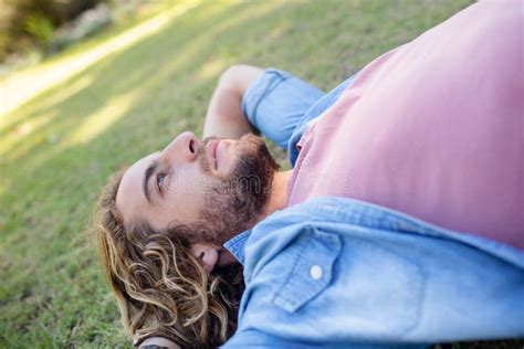 Thoughtful Man Lying On Grass With Hand Behind Head Stock Image Image