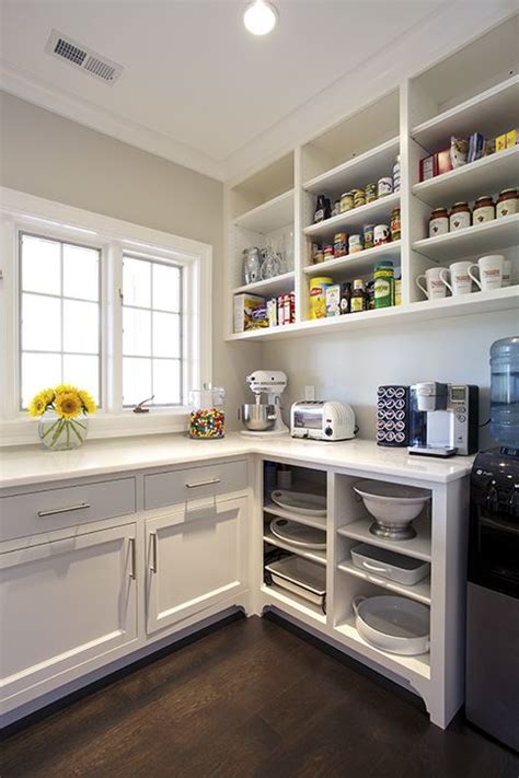 Or, you might be inspired by the kitchen with custom gold shelves framing the stove, decorated with thoughtful pieces. Chic kitchen pantry features white shaker cabinets fitted ...