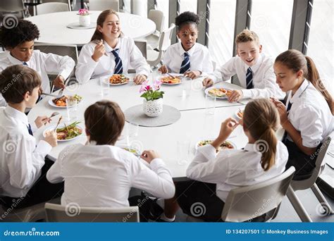 Group Of High School Students Wearing Uniform Sitting Around Table And