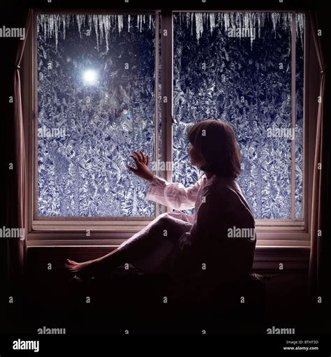 Young Girl Looking Looking Out Window At Star During The Holiday Season