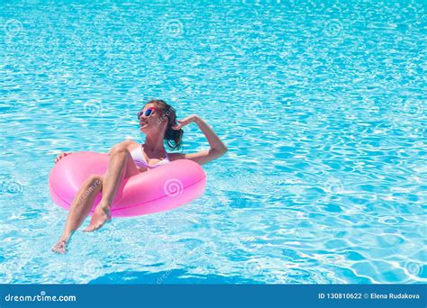 Pretty Woman Floating With Pink Rubber Inflatable Ring In Swimming Pool And Having Fun Stock