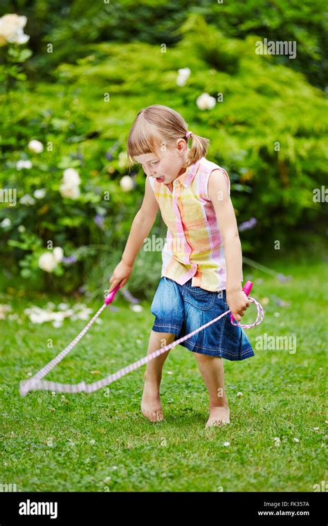 Niña Jugando Con Saltar La Cuerda En El Jardín En Verano Fotografía De