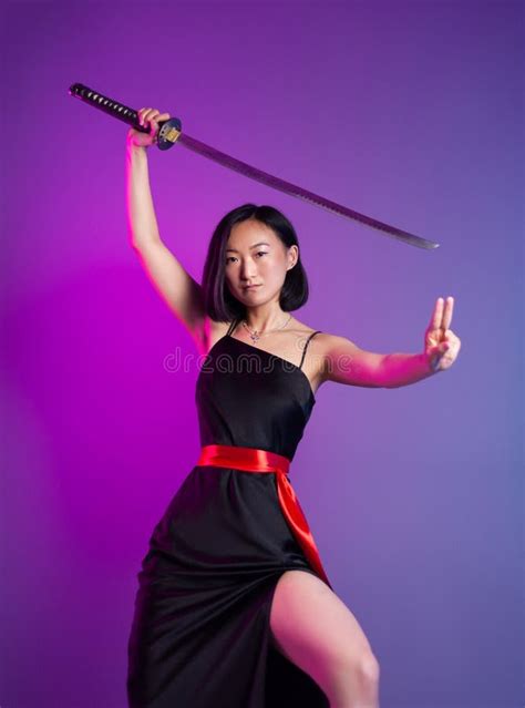 slender asian woman in a black dress with a katana in her hand image of a samurai on a neon