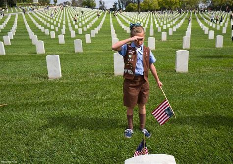 A Girl Scout Salutes After Placing A Flag At A Veterans Gravesite At The Los Angeles National
