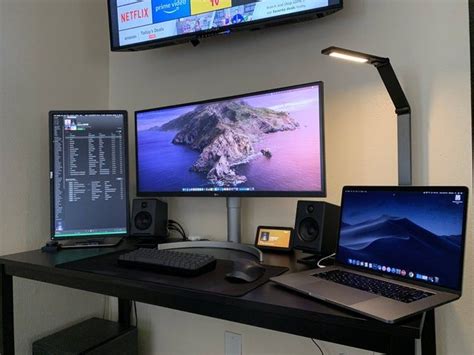 A Desk With Three Monitors And Two Laptops On It In Front Of A Flat