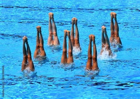 Synchronized Swimmers Point Up Out Of The Water In Action Synchronized