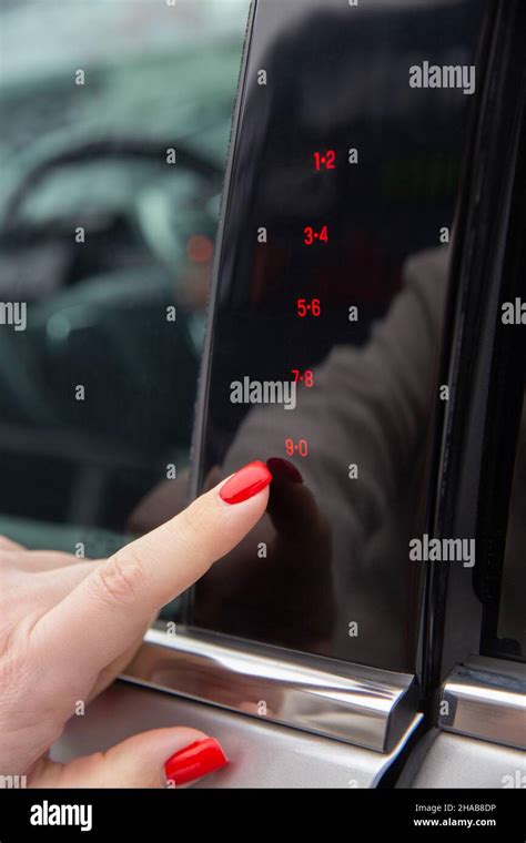 la mano de una mujer introduce el código secreto para abrir la puerta del coche en el panel