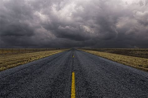 Paved Road Under Cloudy Sky In Remote Landscape Paved Road Under