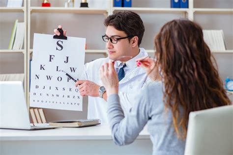The Doctor Optician With Letter Chart Conducting An Eye Test Check