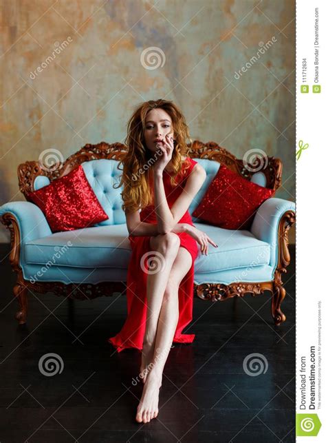 Elegant Sensual Young Brunette Woman In Red Dress Sitting On Leather