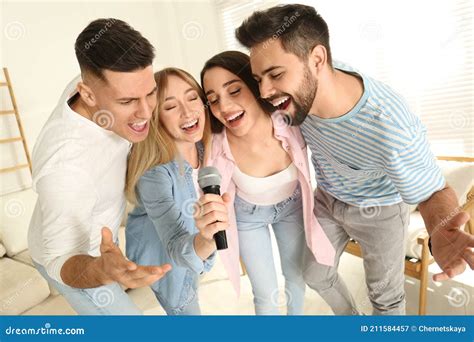 Felices Amigos Cantando Karaoke Juntos En Casa Imagen De Archivo