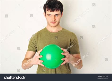 Portrait Of Handsome Man Holding Green Ball In His Arms Standing Near
