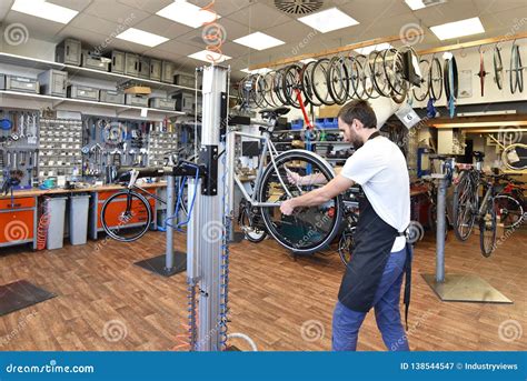 Friendly And Competent Bicycle Mechanic In A Workshop Repairs A Bike