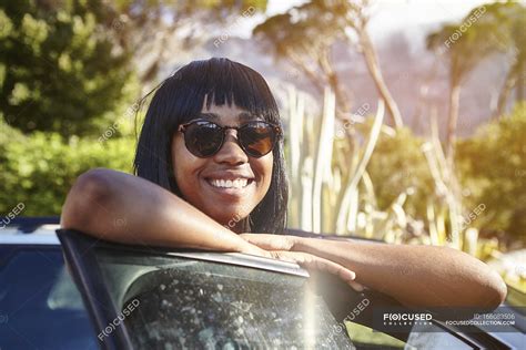 Portrait Of Young Woman Standing Beside Car Leaning On Open Car Door