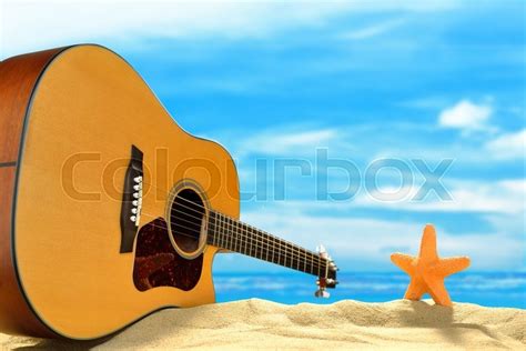 Acoustic Guitar And Starfish On The Beach With Blue Sea And Sky Stock