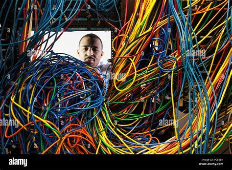 A Black Male Technician Woking On A Tangled Mess Of Cat 5 Cables In A
