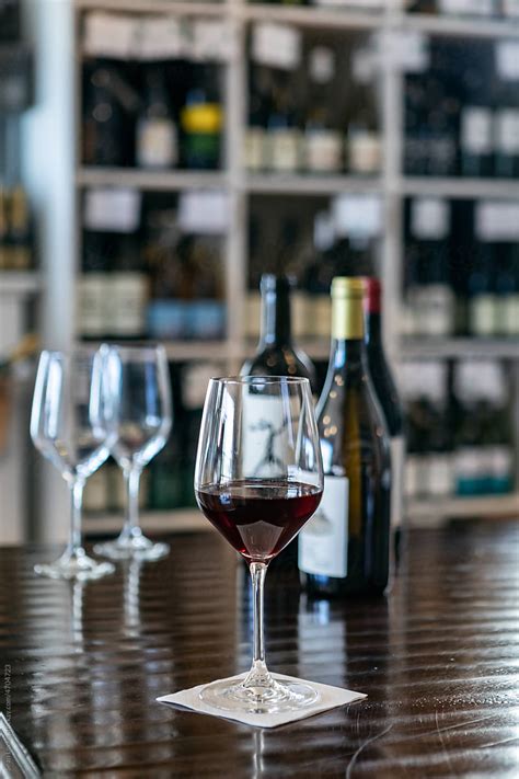 glass of red wine with bottles behind del colaborador de stocksy sean locke stocksy