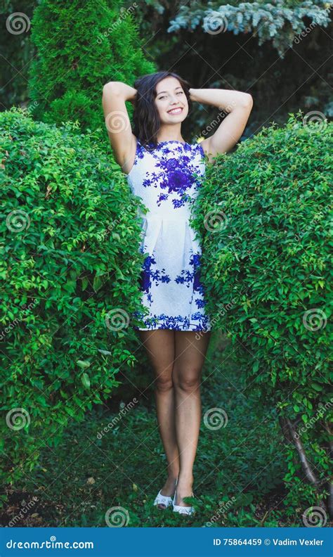 sexig ung flicka mellan två stora buskar i en kort klänning fotografering för bildbyråer bild