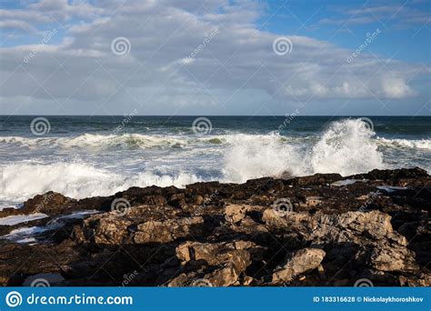 Beautiful Rocky Beach And Ocean Wave Under Blue Cloudy Summer Sky