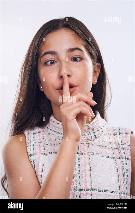 Be Yourself An Attractive Teenage Girl Standing With Her Finger On Her Lips Against A White