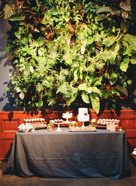 The Table Is Set Up With Desserts And Greenery On It For An Event