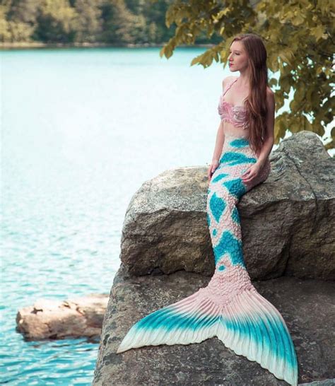 A Woman Sitting On Top Of A Rock Next To A Body Of Water With A Mermaid