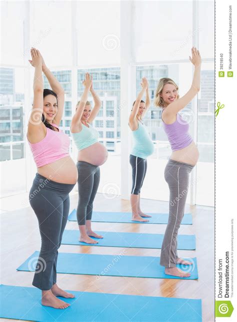 de glimlachende zwangere vrouwen in yogaklasse die zich in boom bevinden stellen het bekijken