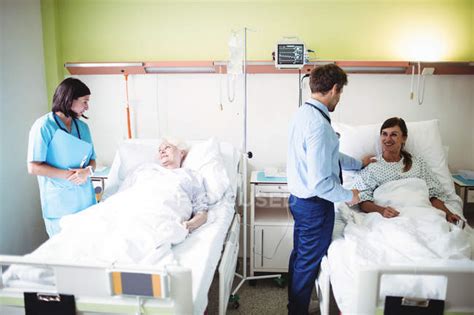 Doctors Interacting With Patients In Hospital Ward — Professionals