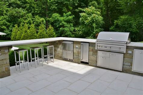 Custom Outdoor Kitchen With Bar Area And Bar Stools Overlooking Pool