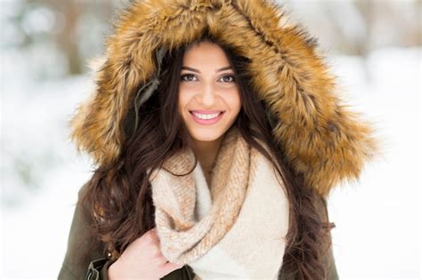 mujer joven y bonita con capucha en el parque en el día de invierno foto premium