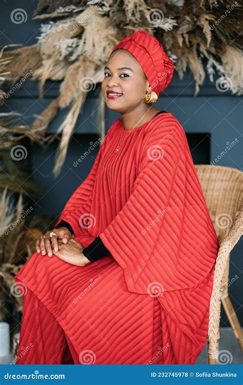 ładna Kobieta W Afryce Ubrana W Czerwony Modny Garnitur I Chustkę Siedzącą Na Krześle W Studio