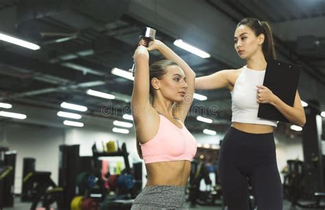 Workout With Personal Trainer Instructor Helping Girl In Gym Stock