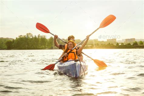 Happy Couple Kayaking On River With Sunset On The Background Stock