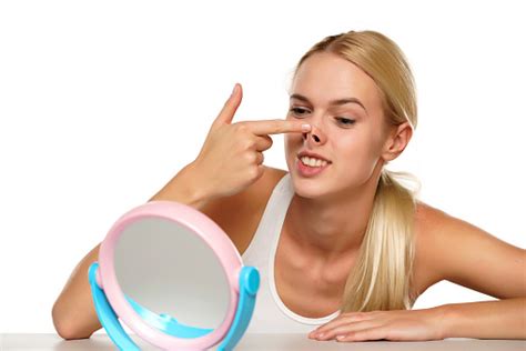 Portrait Of A Young Blond Woman Pushing Up Her Nose In The Mirror Stock