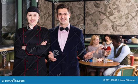 Confident Female Chef Standing In Restaurant Hall With Elegant Waiter