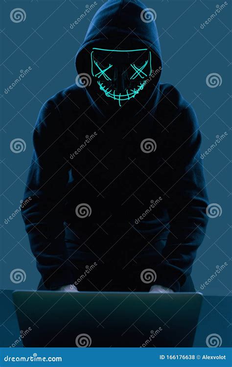 Anonymous Man In A Black Hoodie And Neon Mask Hacking Into A Computer