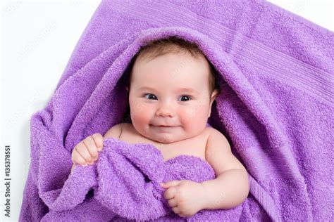Newborn Baby Lying Down And Smiling In A Purple Towel Stock Foto
