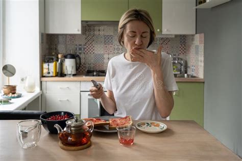 Mature Woman In Home Wear Enjoys Jam Licking Fingers And Eats Toast At