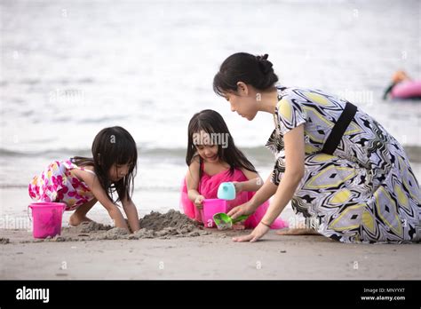 Asian Chinese Mum And Daughters Playing Sand Together At Beach Outdoor