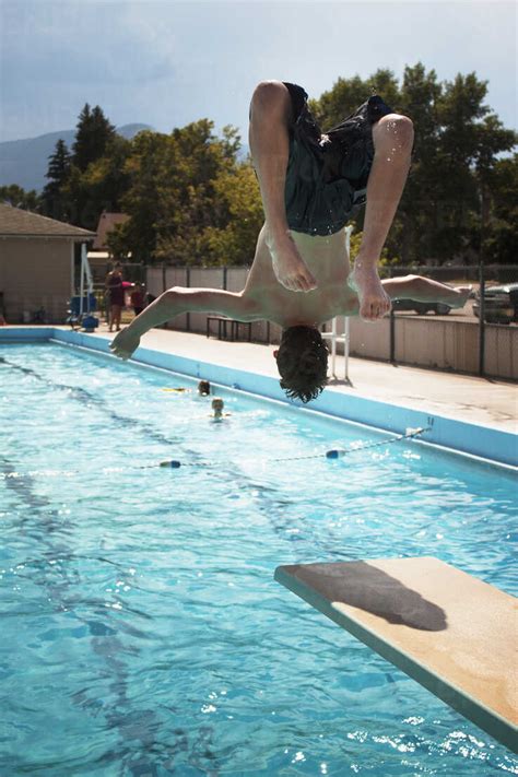 Rear View Of Teenage Boy Jumping In Swimming Pool Stock Photo