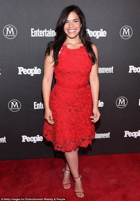 A Woman In A Red Dress Standing On A Red Carpet With Her Hands In Her Pockets