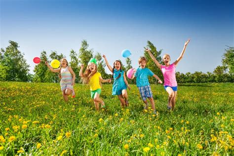 Los Cinco Niños Felices Con Los Globos Corren En Campo Imagen De